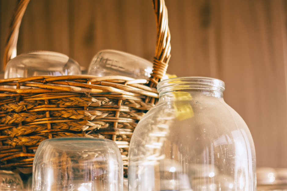 A wicker basket filled with glass jars, warmly lit, capturing a cozy rustic feel.