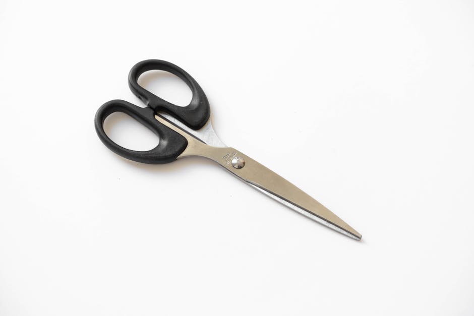 Close-up of stainless steel scissors with black handles on a white background, perfect stationery tool.